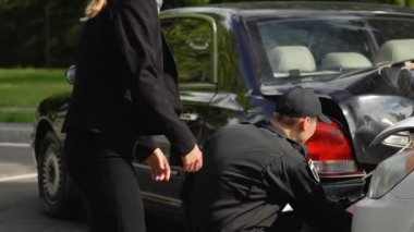 Polis araba kazası inceleyen ve notlar verme, sinirli kadın etrafında yürüyüş