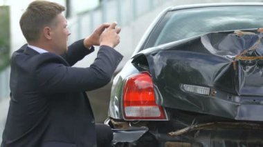 Hasarlı otomobilin fotoğrafını akıllı telefonla çeken erkek sürücü, araç sigortasına dayanıklı