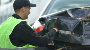 Hasarlı otomobilin tabletle fotoğraflarını çeken erkek polis memuru, online uygulama