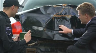 Hasarlı otomobilin tablet fotoğrafını çeken erkek memur, üzgün sürücünün otomobili parçaladı