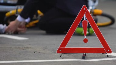 Yolda yol tehlike işareti, adam bilinçsiz bisikletçi arka plan nabız kontrol