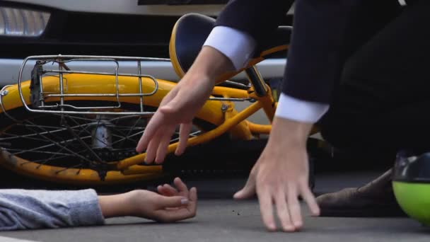 Hombre midiendo pulso en hembra golpeada yaciendo en camino de asfalto cerca de bicicleta, colisión — Vídeo de stock