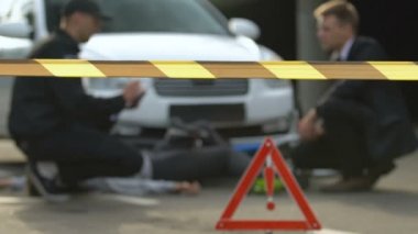 Memur uyarı bandı arkasında erkek sürücü konuşurken araba kazası raporu yazma