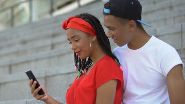 Афро-американская пара подростков держит смартфон, онлайн-покупки вместе — стоковое видео