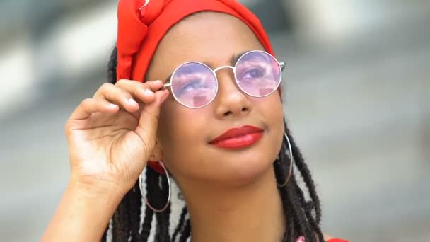 Прелестная черная девочка-подросток смотрит на небо через солнцезащитные очки, наслаждаясь видом на природу — стоковое видео