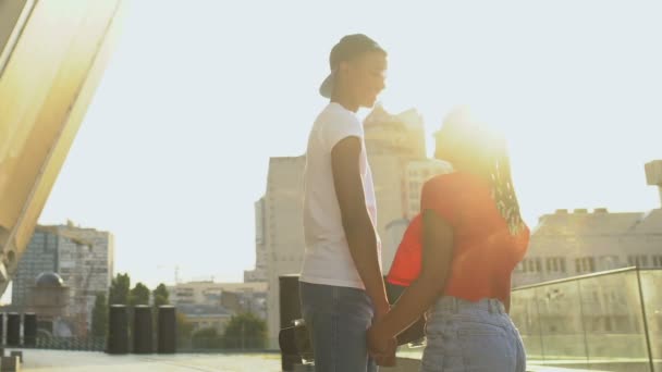 Svart tonåring par i casual kläder hålla händer, promenader gata på solnedgången — Stockvideo