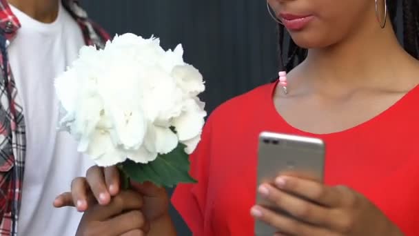 Svart tonåring flicka chatta på smartphone ignorera pojkvän presentera blommor — Stockvideo