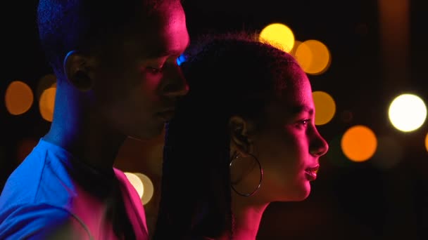 Fiatal afro-amerikai fiú ölelkező barátnő hátulról, élvezi éjszakai városi kilátás — Stock videók