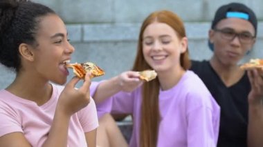 En iyi arkadaşlarıyla lezzetli pizza yiyen melez bir kız, fast food atıştırmalığı.