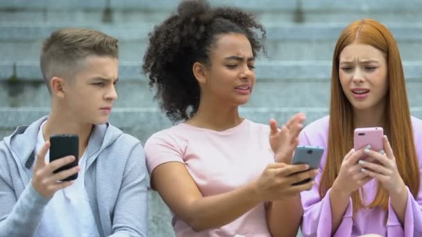 Afro-americana chica disgustado con mal foto comentario mostrando teléfono a amigos — Vídeos de Stock
