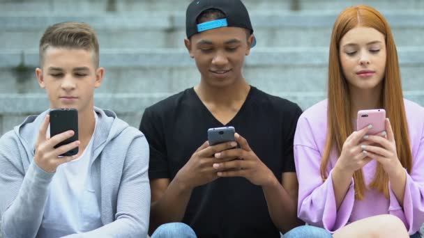 Amigos charlando en redes sociales en teléfonos al aire libre, adolescente alegre compartir noticias — Vídeo de stock
