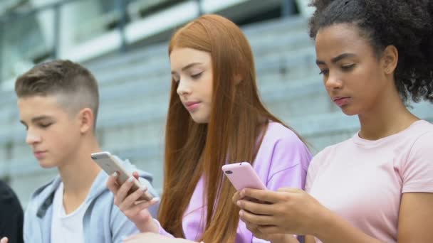 Smartphone adolescentes viciados usando gadgets ao ar livre, falta de comunicação real — Vídeo de Stock