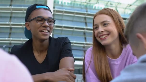 Blank meisje en Afrikaans-Amerikaanse man praten met vrienden buiten, sympathie — Stockvideo