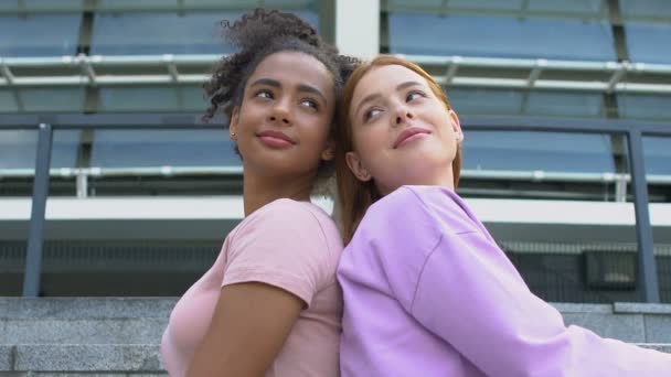 Beste vrouwelijke vrienden die achterover leunen en glimlachen naar elkaar, sterke vriendschap — Stockvideo