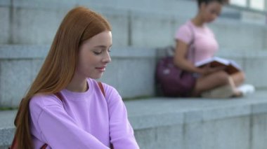 Genç adam merdivenlerde uzanan güzel, uzun saçlı kız öğrenciye kur yapıyor.