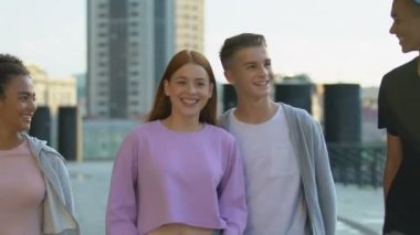 Heyecanlı çok ırklı arkadaşlar şakalaşıyor ve gülüyorlar, birlikte yürüyorlar, mutlu eğlenceler.