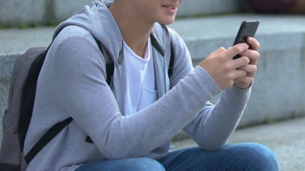 Rilassato studente caucasico maschio scorrimento social network sulle scale del campus, app — Video Stock