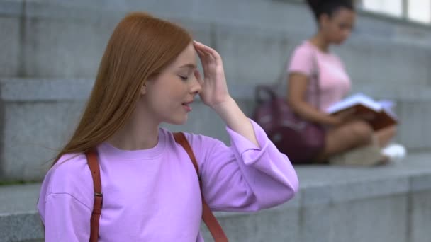 Utangaç, uzun saçlı kız öğrenci kampüs merdivenlerinde sınıf arkadaşıyla flört ediyor. — Stok video
