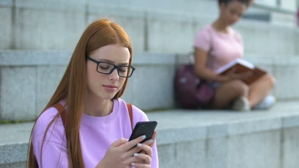 Szomorú kaukázusi lány szemüveg üzenetküldés szociális hálózatok mobiltelefon — Stock videók