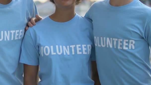 Çok kültürlü gönüllü gençlerden oluşan heyecanlı bir grup kamerada sarılıp gülümsüyor. — Stok video