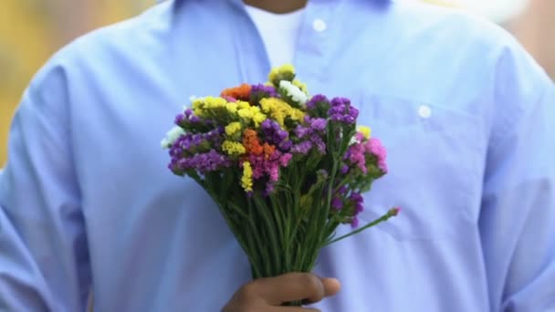 Young gentleman presenting beautiful bouquet of flowers to camera, pleasant gift — Stock Video