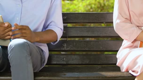 Shy students sitting closer on park bench, trying to get acquainted, first love — Stock Video