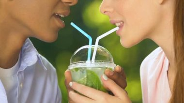 Birbirine aşık öğrenci çift bir fincan romantik randevudan taze pipet kokteyli içiyor.