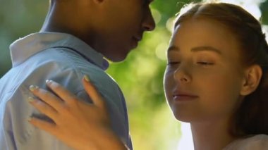 Güneş ışığı ve romantik atmosferle aydınlanan genç çiftin yakınlaşması