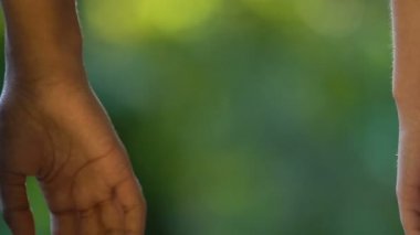 Erkek ve kadın elleri yeşil arka plana sıkıca tutunuyor, destekleyici bir arkadaş.