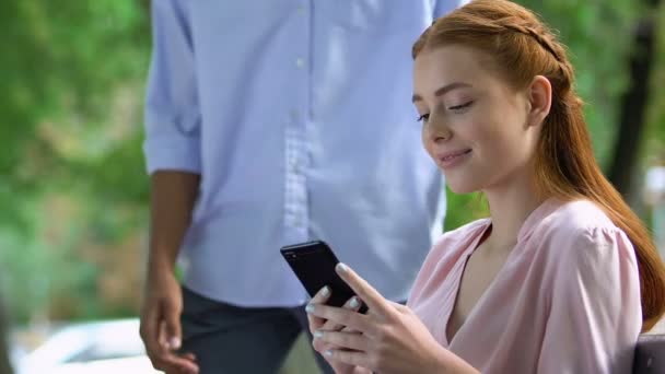 Друг насмехается над девушкой, используя мобильный телефон, одержимый социальной сетью, зависимостью — стоковое видео