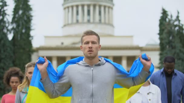 Активисты, поднимающие украинский флаг, скандирующие лозунг, митинг за независимость, патриотизм — стоковое видео
