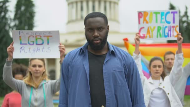 Zwarte man met regenboog symbolen te midden van demonstranten voor Lgbt rechten, trots gebeurtenissen — Stockvideo