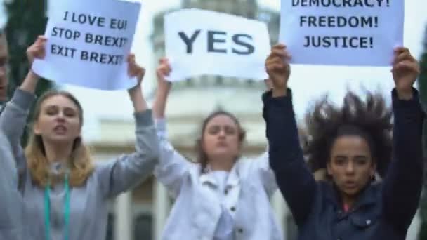 Joven sostiene bandera de la Unión Europea, activistas con lemas de libertad en el fondo — Vídeos de Stock