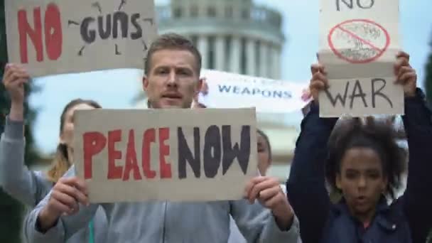 Ακτιβιστές ανεμίζουν πανό διαμαρτυρόμενοι ενάντια σε μαζικούς πυροβολισμούς, πυρηνικά όπλα, πόλεμο — Αρχείο Βίντεο
