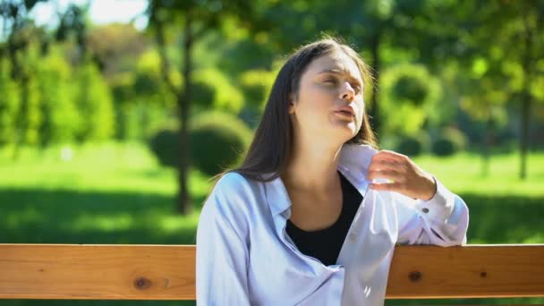 Mujer joven descansando en el banco en el parque, sufriendo de calor y congestión, pms — Vídeos de Stock