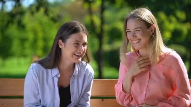 Mejores amigas sinceramente sonriendo pasar tiempo en el banco en el parque, amistad — Vídeo de stock