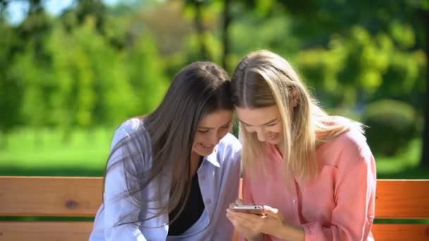 Två roliga kvinnliga vänner rulla och diskutera bilder av män i dating app — Stockvideo