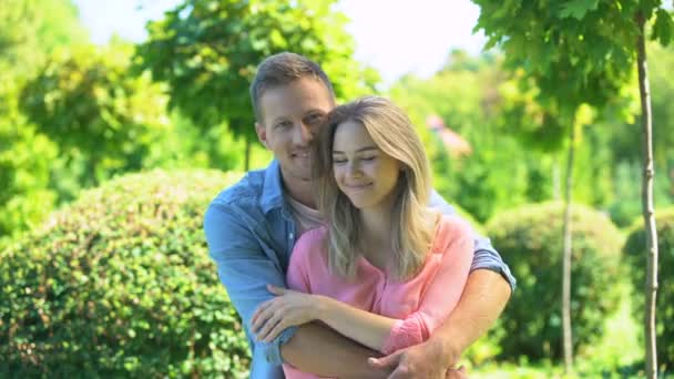 Привлекательная влюбленная пара улыбается и обнимается перед камерой, отношения — стоковое видео