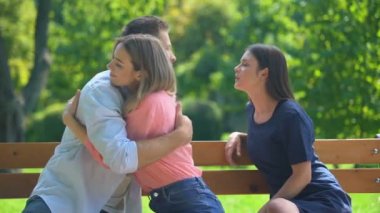 Erkek arkadaşı sevgilisine sarılıyor ve gizlice arkadaşını öpüyor. Gizli ilişkileri var.