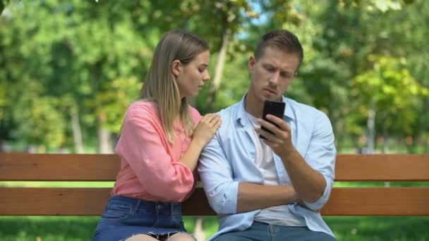 Tjejen försöker dra till sig uppmärksamhet från pojkvännen som spelar i telefon och ignorerar henne — Stockvideo
