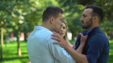 Endişeli kadın kıskanç erkek arkadaşı başka bir adamla kavga etmemeye çalışıyor.