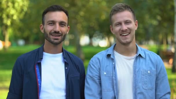 Melhores amigos masculinos abraçando e sorrindo para a câmera ao ar livre, relações alegres — Vídeo de Stock