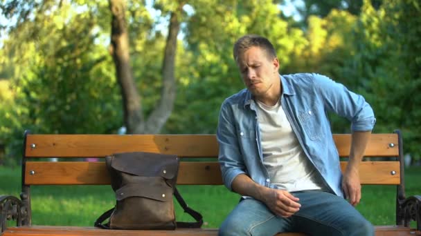 Muž sedí na lavičce trpí milenec bolesti zad po traumatu nebo zranění — Stock video
