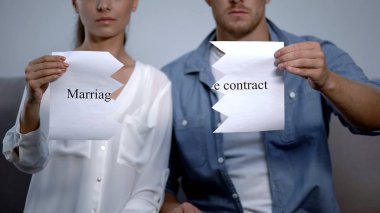 Serious couple tearing into pieces marriage contract phrase on cardboard clipart