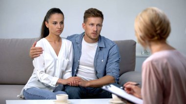 Üzgün çift psikolog danışma el ele tutuşarak, aile girişimi tasarruf