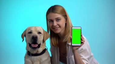 Kamera, evcil hayvan evlat edinme uygulaması cep telefonu gösteren safkan köpek ile Neşeli kadın