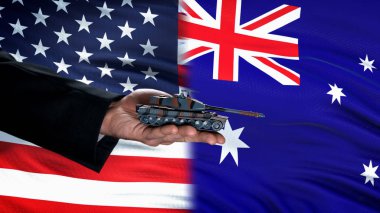 Abd ve Avustralya bayrağına karşı resmi el tutan oyuncak tankı, silah ticareti