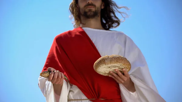 Man in robe holding fish and bread, charity concept to feed hungry, generosity — Stock Image Man Robe Holding Fish Bread Charity Concept Feed Hungry Generosity Royalty Free Stock Photos