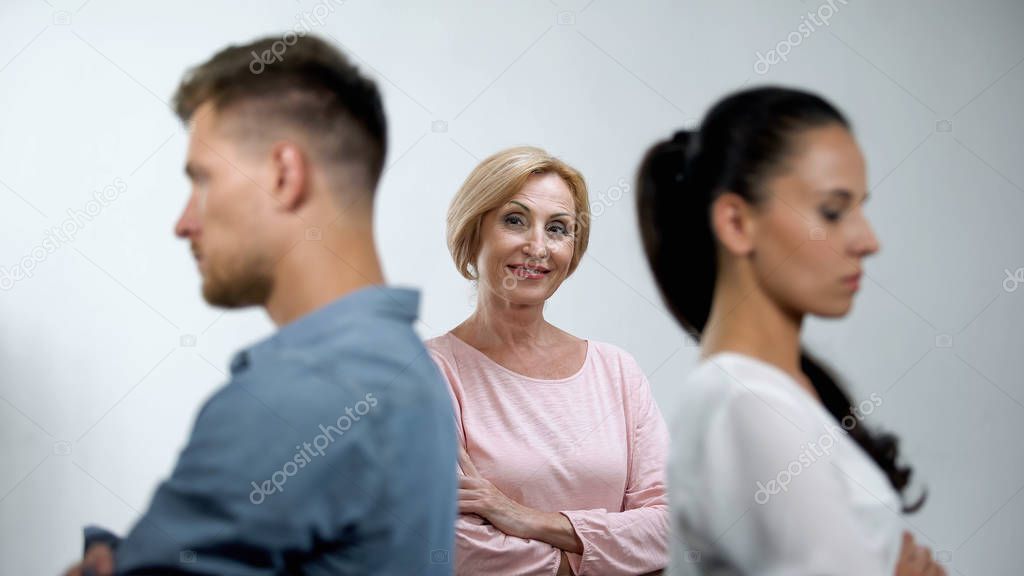Satisfied mother looking at couple in quarrel standing back to each other