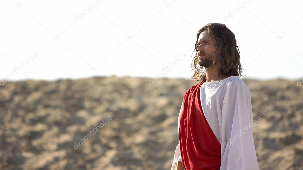 Jesus Christ in white robe watching city in desert area, historical event